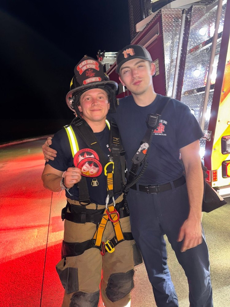 Two Gilmer County Fire/Rescue firefighters with A-Shift patches in front of an engine at night