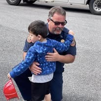 A Gilmer County Fire/Rescue firefighter greeting a child at a community event