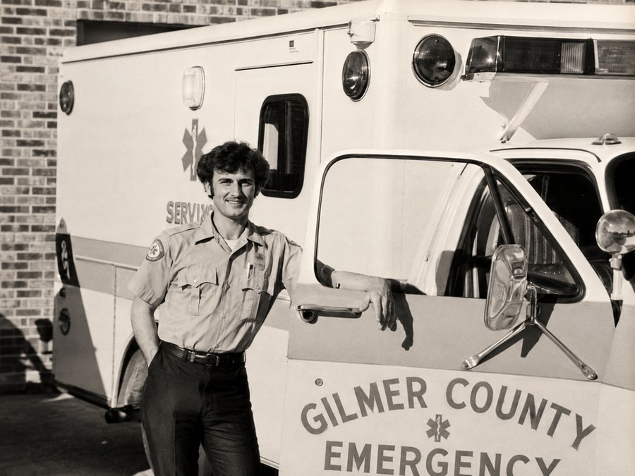 Historical photo of a Gilmer County EMT with an early ambulance