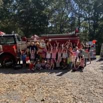 Group of kids in front of a Gilmer County Fire/Rescue fire engine at a community event