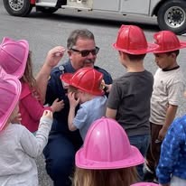 A Gilmer County Fire/Rescue firefighter fitting a child with a junior firefighter helmet