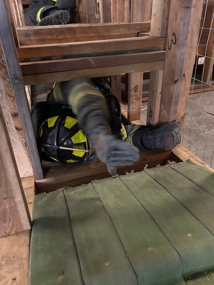 Firefighter crawling through a search-training maze prop