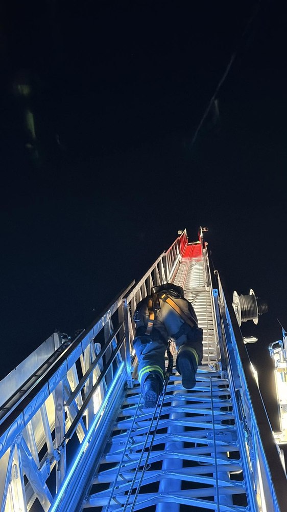 Firefighter climbing the aerial ladder at night