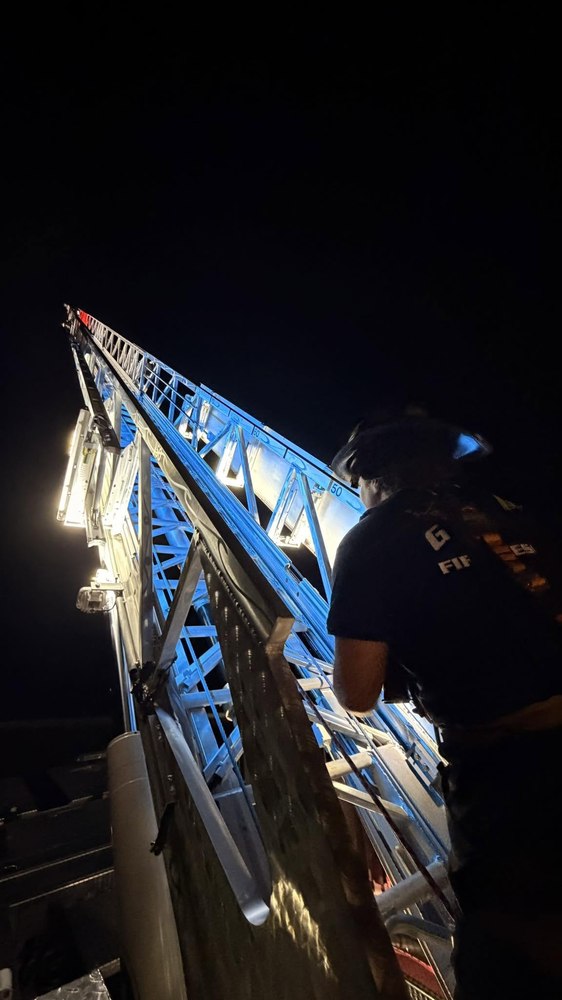 Firefighter on the aerial ladder at night, lit in blue