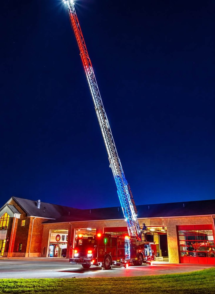 Gilmer County Fire/Rescue aerial ladder truck extended and lit up at night outside the station