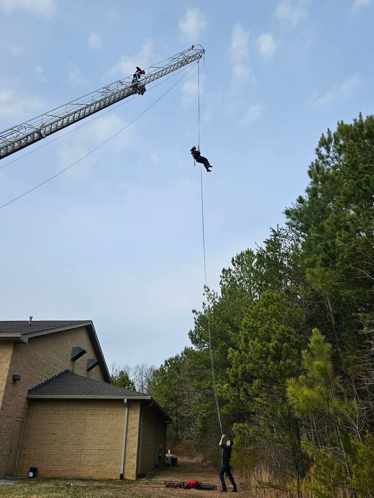 Firefighter rappelling from an aerial ladder during high-angle rope rescue training