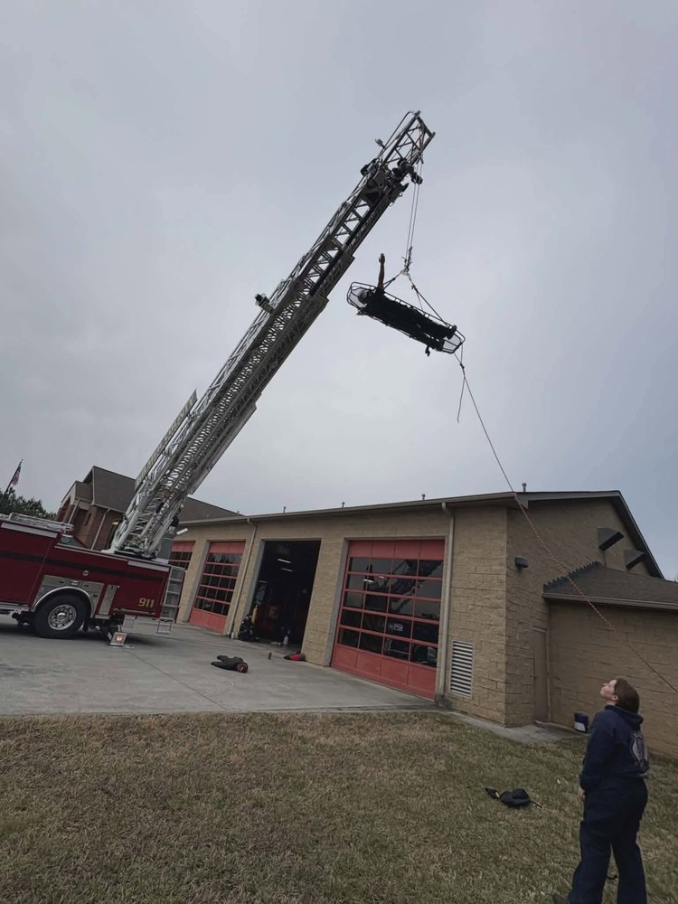 A Stokes rescue basket being lowered from an aerial ladder during technical rescue training