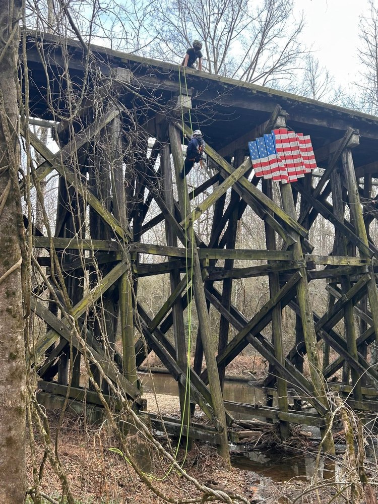 Firefighters rappelling from a wooden rail trestle during rope rescue training