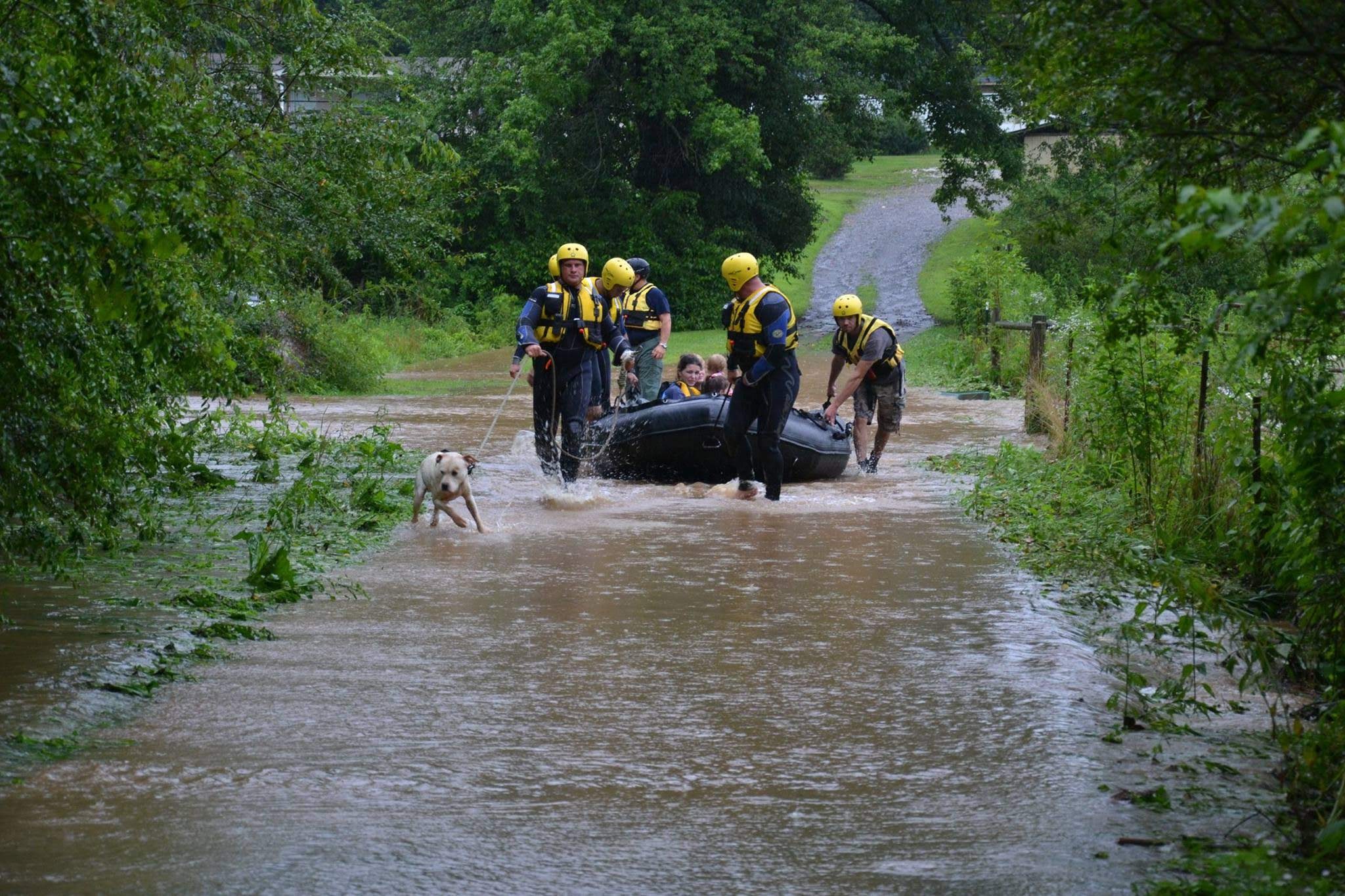 Gilmer County Fire/Rescue swift water rescue crew guiding a boat with a family and their dog through floodwater